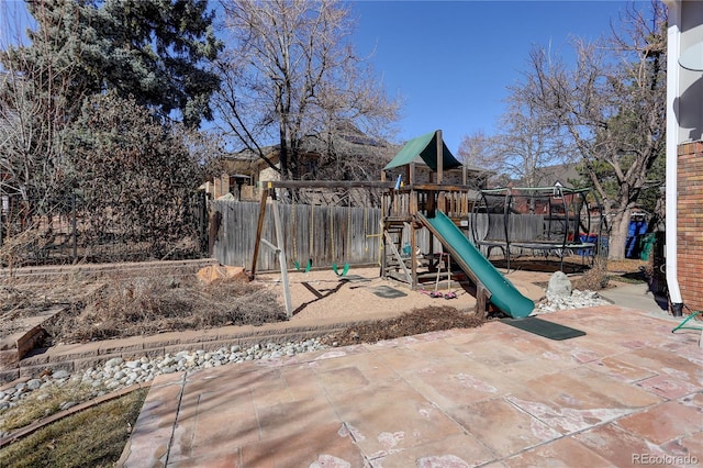 view of playground with a trampoline, fence, and a patio