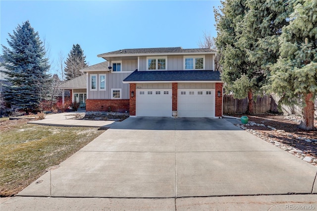 view of front of house featuring board and batten siding, brick siding, driveway, and fence