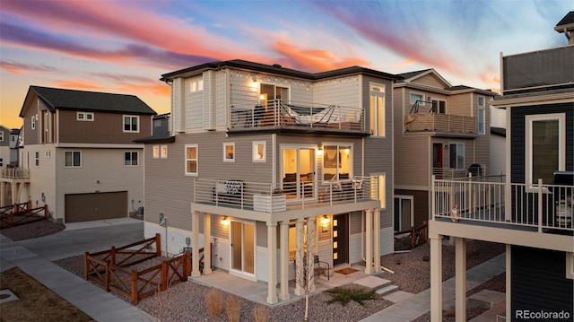 rear view of property featuring a balcony, an attached garage, and driveway