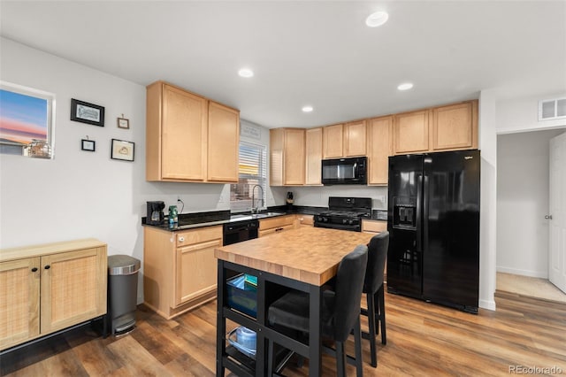 kitchen featuring visible vents, dark wood-style flooring, a sink, light brown cabinetry, and black appliances