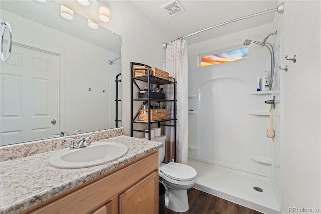 full bathroom with visible vents, a shower stall, toilet, wood finished floors, and vanity