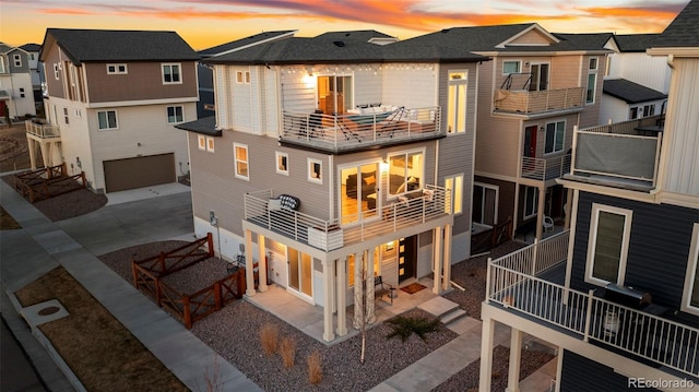 back of house at dusk with a garage, a residential view, and driveway