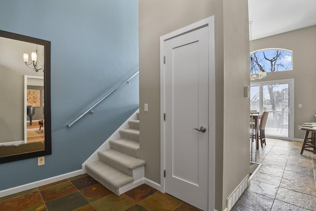 stairs with baseboards, visible vents, a chandelier, and stone tile flooring