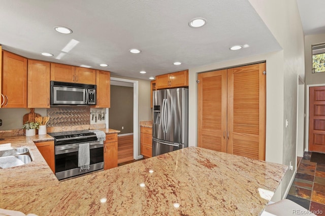 kitchen with light stone counters, recessed lighting, and stainless steel appliances