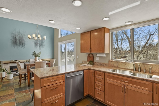 kitchen with a sink, stainless steel dishwasher, a peninsula, and stone tile floors