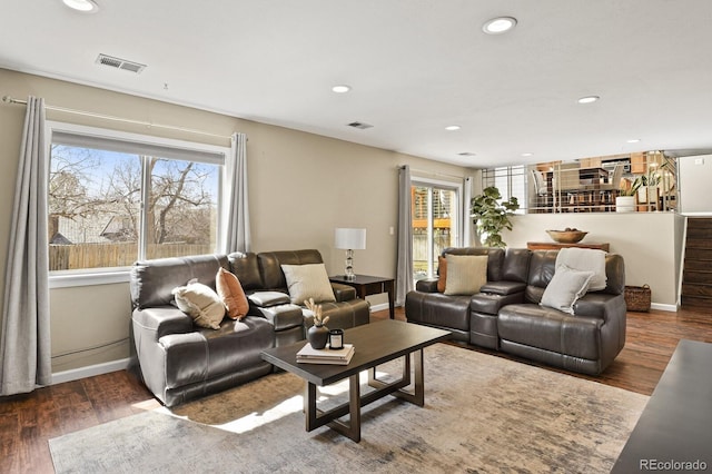 living area with a wealth of natural light, visible vents, and wood finished floors