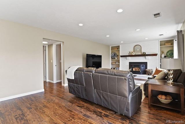 living area featuring built in shelves, dark wood-style floors, visible vents, baseboards, and recessed lighting