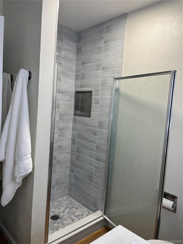 full bath featuring a stall shower and a textured wall