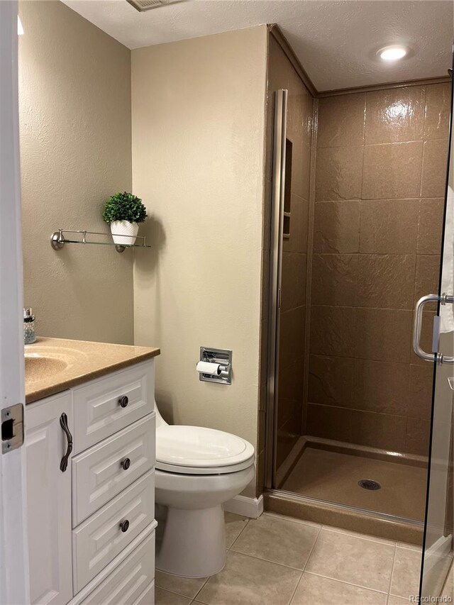 bathroom with vanity, a stall shower, tile patterned flooring, a textured ceiling, and toilet