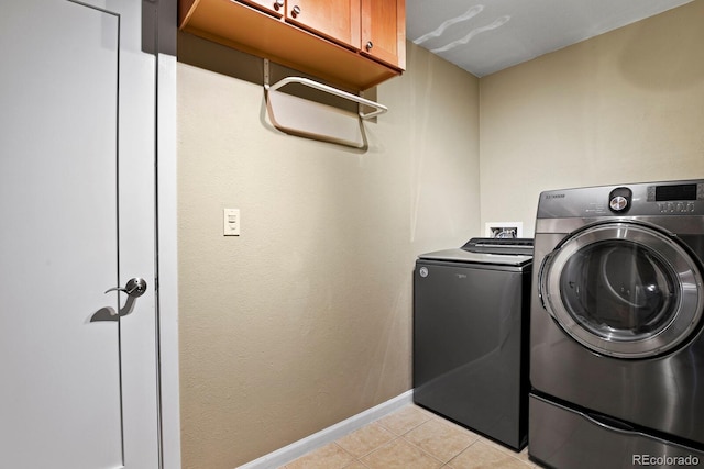 laundry area featuring light tile patterned floors, cabinet space, independent washer and dryer, and baseboards