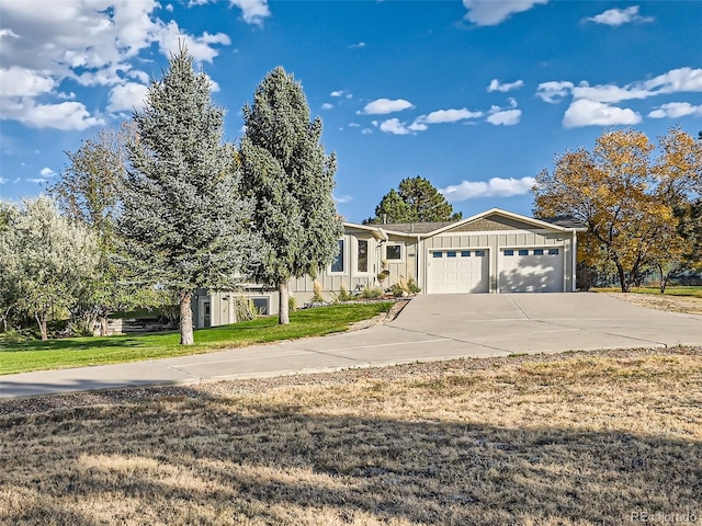 view of front of home with a garage, driveway, a front lawn, and board and batten siding