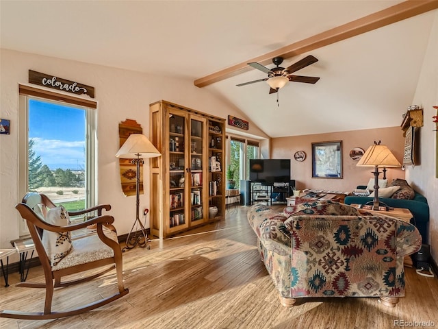 living area featuring a ceiling fan, vaulted ceiling with beams, and wood finished floors