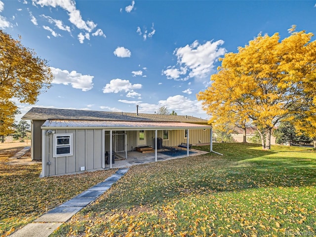 rear view of house with a patio, a yard, and board and batten siding