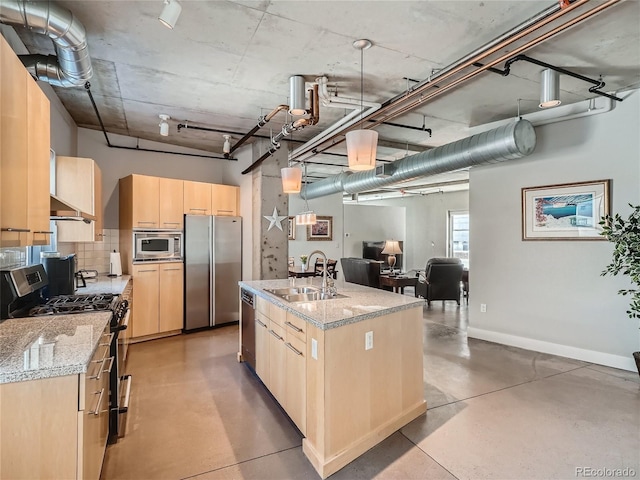 kitchen featuring light brown cabinets, light stone countertops, stainless steel appliances, a center island with sink, and sink