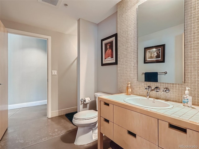 bathroom featuring tasteful backsplash, toilet, vanity with extensive cabinet space, and concrete floors