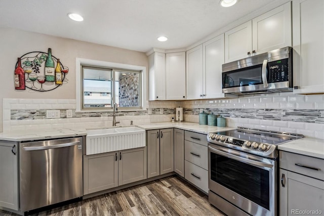 kitchen with sink, gray cabinetry, stainless steel appliances, dark hardwood / wood-style floors, and tasteful backsplash