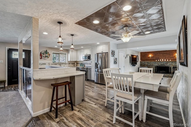 dining space featuring ceiling fan, wood-type flooring, sink, and a textured ceiling