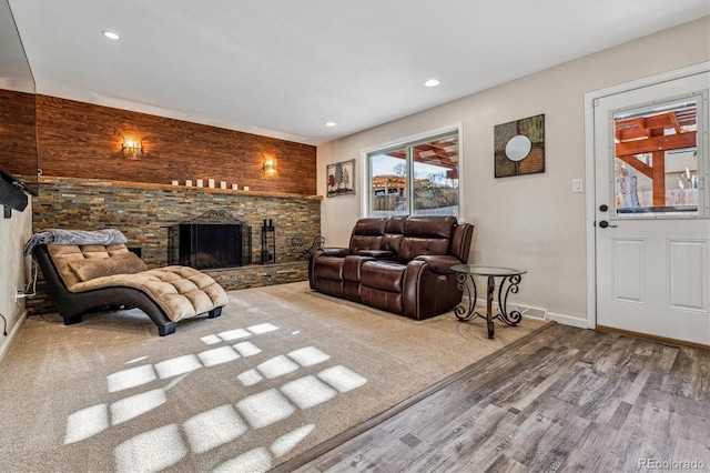 living room with a stone fireplace and wood-type flooring