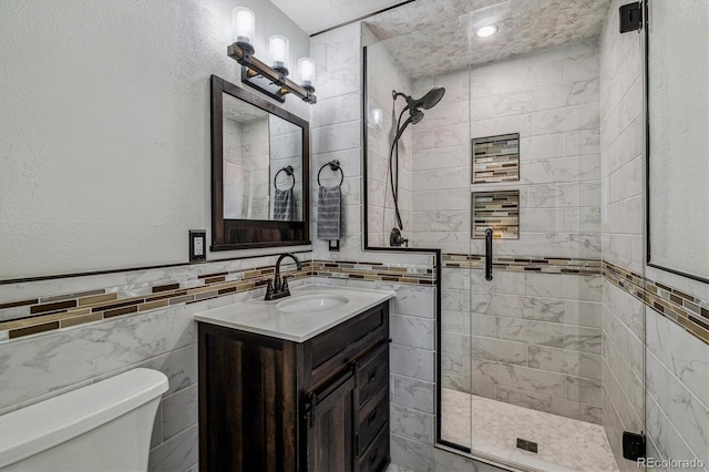 bathroom featuring walk in shower, vanity, toilet, and tile walls