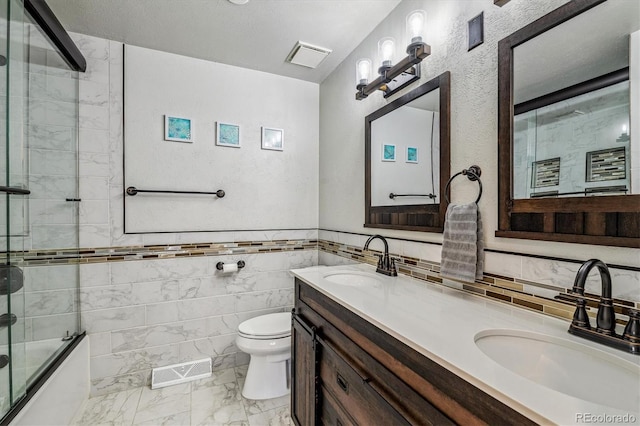 full bathroom with vanity, combined bath / shower with glass door, tile walls, and toilet