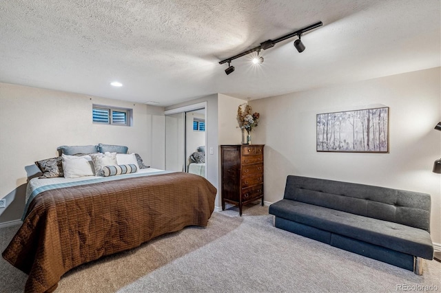 carpeted bedroom featuring track lighting, a closet, and a textured ceiling