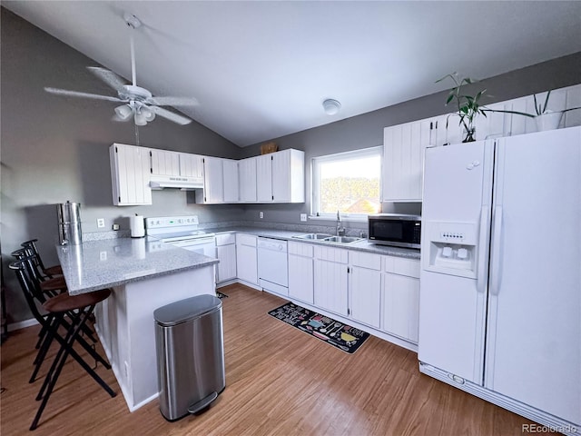 kitchen featuring a sink, wood finished floors, white appliances, a peninsula, and under cabinet range hood