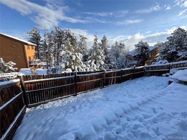 snowy yard featuring a fenced backyard