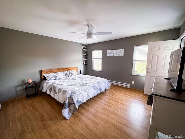 bedroom with a baseboard heating unit, ceiling fan, and light wood-type flooring