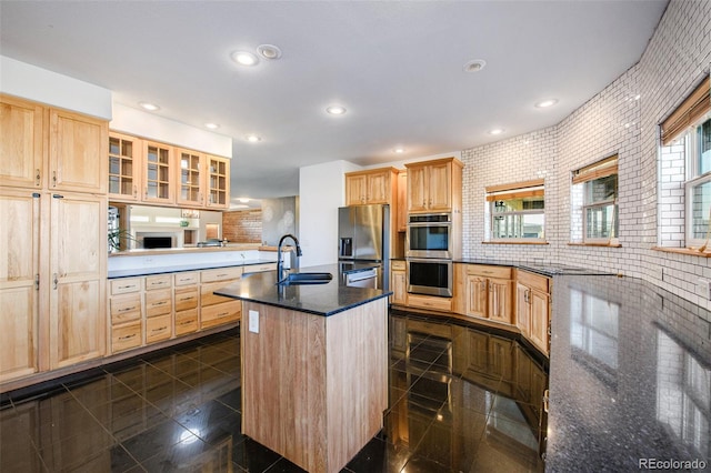 kitchen with a kitchen island with sink, a healthy amount of sunlight, brick wall, and sink