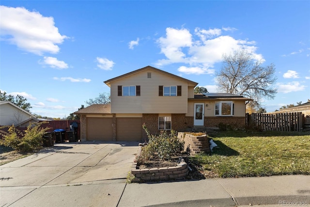 split level home with solar panels, a garage, and a front yard