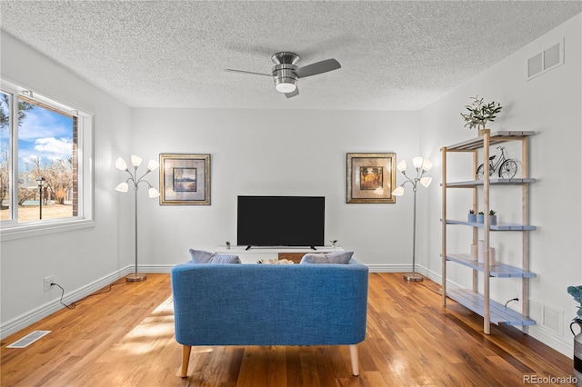 living area featuring a ceiling fan, light wood-type flooring, and visible vents