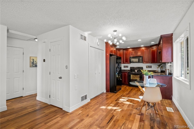 kitchen featuring visible vents, dark brown cabinets, a sink, and black appliances