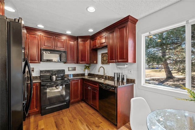 kitchen featuring reddish brown cabinets, a healthy amount of sunlight, a sink, and black appliances