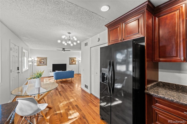 kitchen featuring a textured ceiling, visible vents, black fridge, light wood-type flooring, and reddish brown cabinets