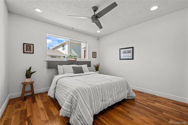 bedroom with recessed lighting, a textured ceiling, baseboards, and wood finished floors