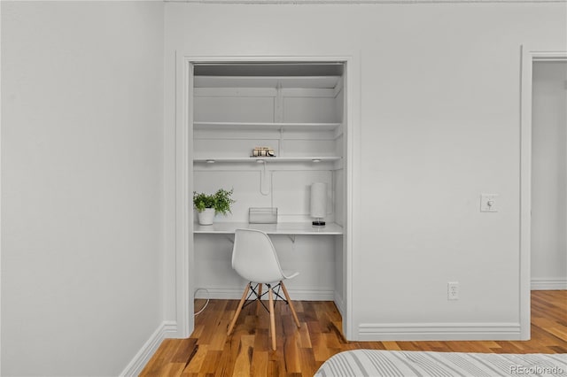 interior space with baseboards, wood finished floors, and built in study area