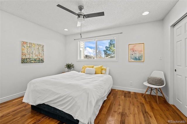 bedroom featuring a textured ceiling, recessed lighting, wood finished floors, and baseboards