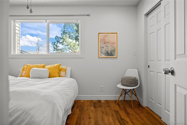 bedroom with a closet, wood finished floors, and baseboards