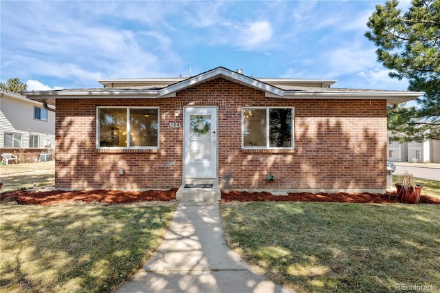 bungalow with a front yard and brick siding