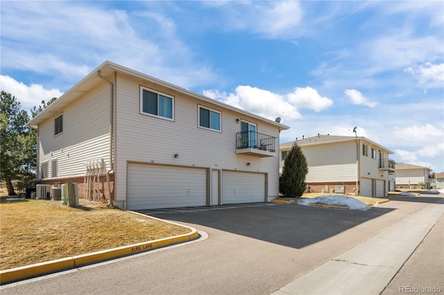 view of front of house with a garage, driveway, cooling unit, and a balcony