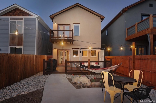 656 S Gunnison Ave, Buena Vista, CO 81211 - back of house at night with a balcony, a patio area, stucco siding, and a fenced backyard