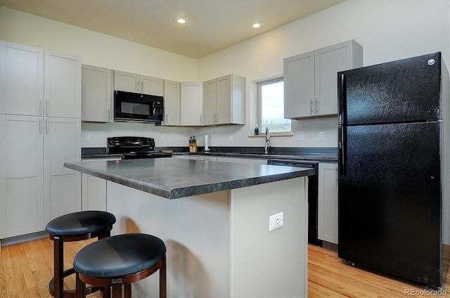 656 S Gunnison Ave, Buena Vista, CO 81211 - kitchen featuring dark countertops, a breakfast bar area, black appliances, and light wood-type flooring