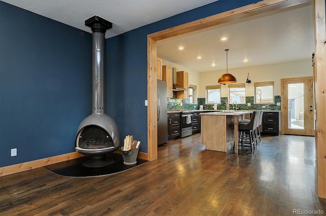 656 S Gunnison Ave, Buena Vista, CO 81211 - kitchen with dark wood-style flooring, a breakfast bar, appliances with stainless steel finishes, and decorative backsplash