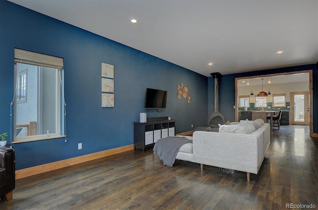 656 S Gunnison Ave, Buena Vista, CO 81211 - living area featuring recessed lighting, plenty of natural light, baseboards, a wood stove, and dark wood-style floors
