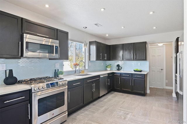 kitchen featuring pendant lighting, backsplash, sink, light tile patterned flooring, and stainless steel appliances