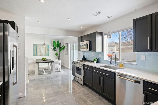 kitchen featuring appliances with stainless steel finishes, backsplash, hanging light fixtures, and sink