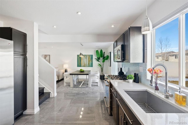 kitchen featuring tasteful backsplash, sink, hanging light fixtures, and appliances with stainless steel finishes