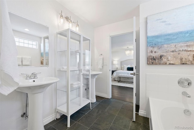 bathroom featuring a tub to relax in, sink, an inviting chandelier, and tile patterned flooring