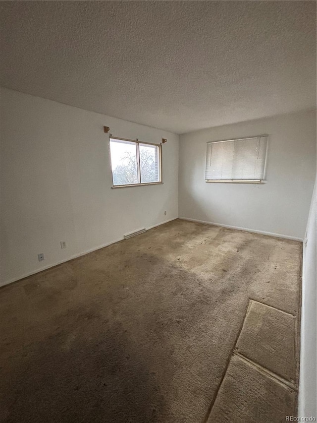 carpeted spare room with a textured ceiling