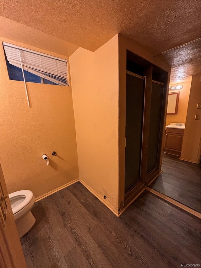 bathroom featuring vanity, an enclosed shower, wood-type flooring, and a textured ceiling